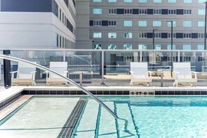 A swimming pool with lounge chairs and a glass railing. - The Louie - Luxe 1BR Condo DT w/ Rooftop Pool, Gym (Orlando)