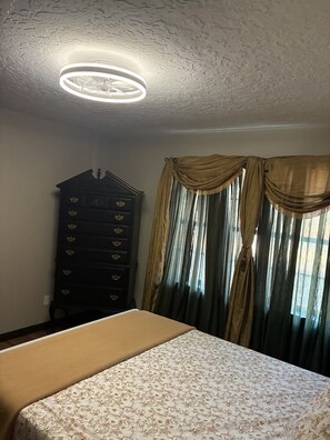 Ein Schlafzimmer mit einem Bett, einem Schminktisch und Vorhängen.