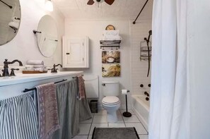 Une salle de bain avec un lavabo blanc, un miroir, des toilettes et une baignoire.
