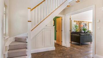 A staircase with carpeted steps and white railings, leading to a room with a herringbone floor pattern.