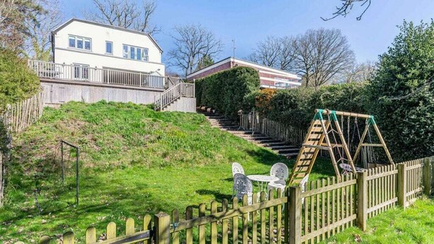 Ein Wohngebiet mit einem Haus, einem Holzzaun, einer Schaukel und einem kleinen Garten.