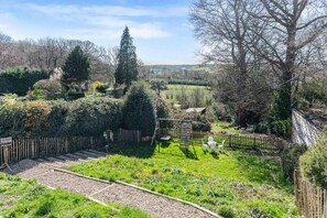 A garden with a wooden fence, a swing set, and a variety of plants and trees. - Bromley Retreat: Spacious Townhouse w/Parking (Bromley)