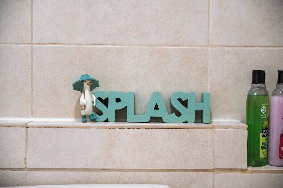 Ein Badezimmer mit einem Regal, das eine Dekoration und zwei Seifenspender trägt.