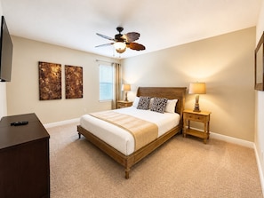 A bedroom with a bed, bedside tables, a ceiling fan, artwork on the wall, and a TV. - Reunion Resort 6BR Pool Home & Game Room (Kissimmee)