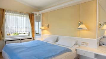 Ein Hotelzimmer mit Bett, Nachttischen, einem Fenster mit Vorhängen und Wandlampen.