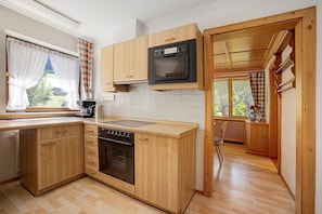 A compact kitchen with wooden cabinets, a built-in microwave, and a dishwasher.