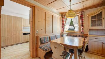 A wooden interior with a dining table, benches, and a kitchen area.