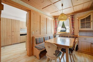 A wooden interior with a dining table, benches, and a kitchen area.