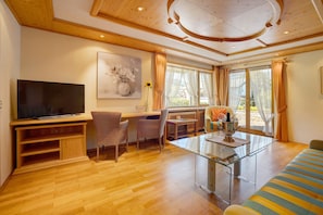 A spacious living area with a flat-screen TV, a dining table, and a sofa.