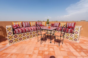 An outdoor seating area with a sofa and table, surrounded by patterned tiles.