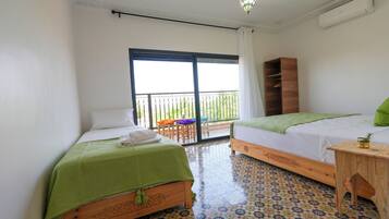 A hotel room with two beds, a balcony, a wooden nightstand, and a patterned floor.
