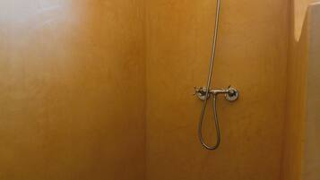 Une salle de bain avec douche, carrelage au sol et agencement d’angle.