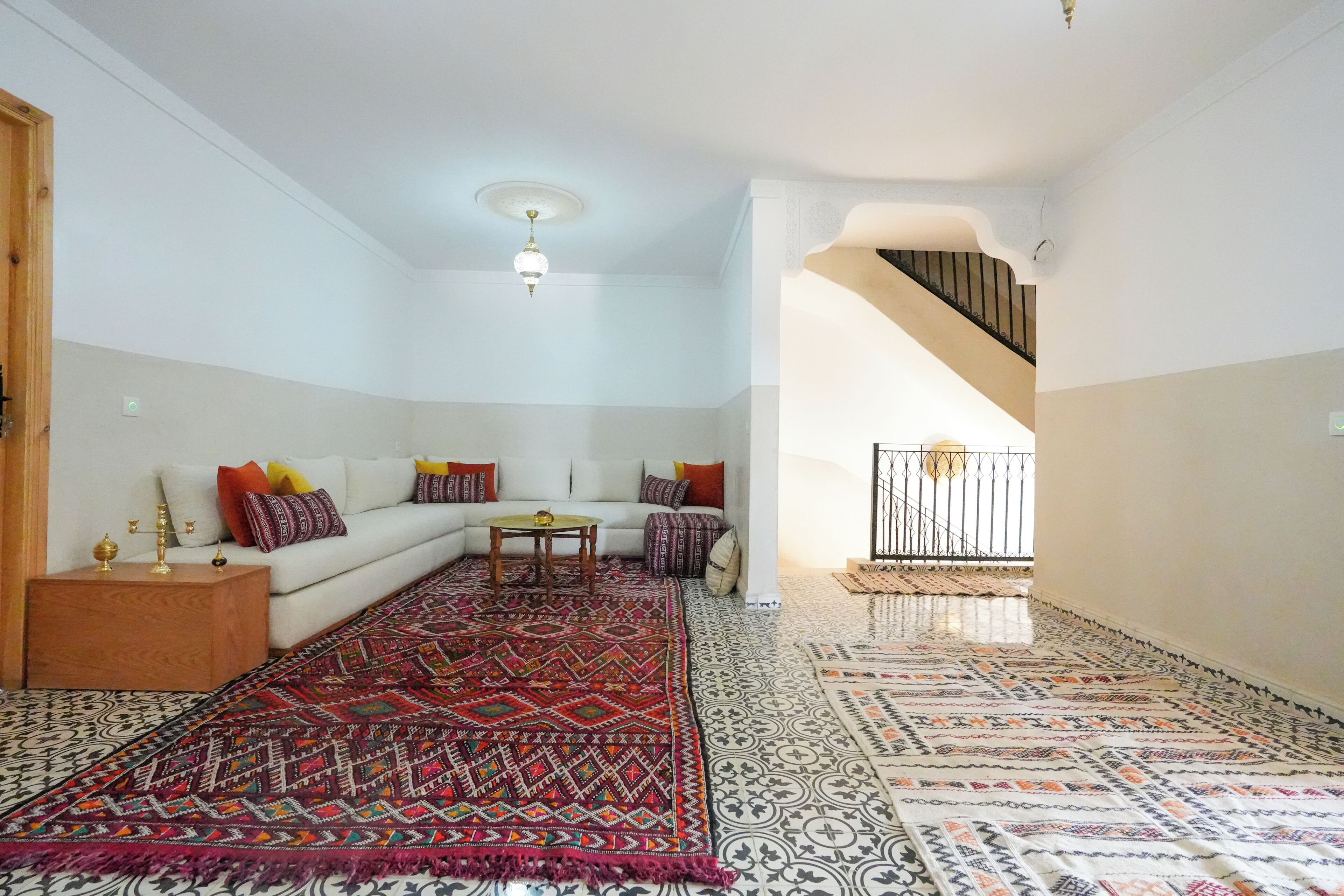 Una sala de estar con un tapete estampado, un sofá blanco y una mesita.