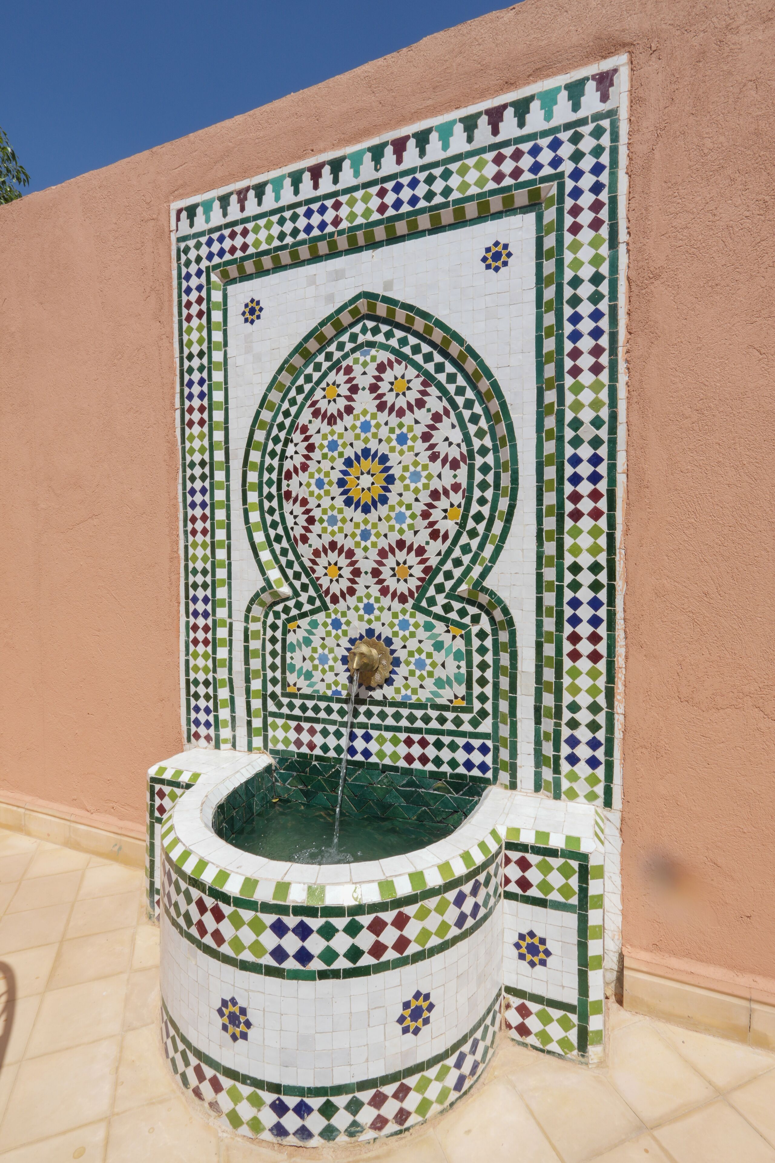 A tiled fountain with a geometric pattern and a central water spout.