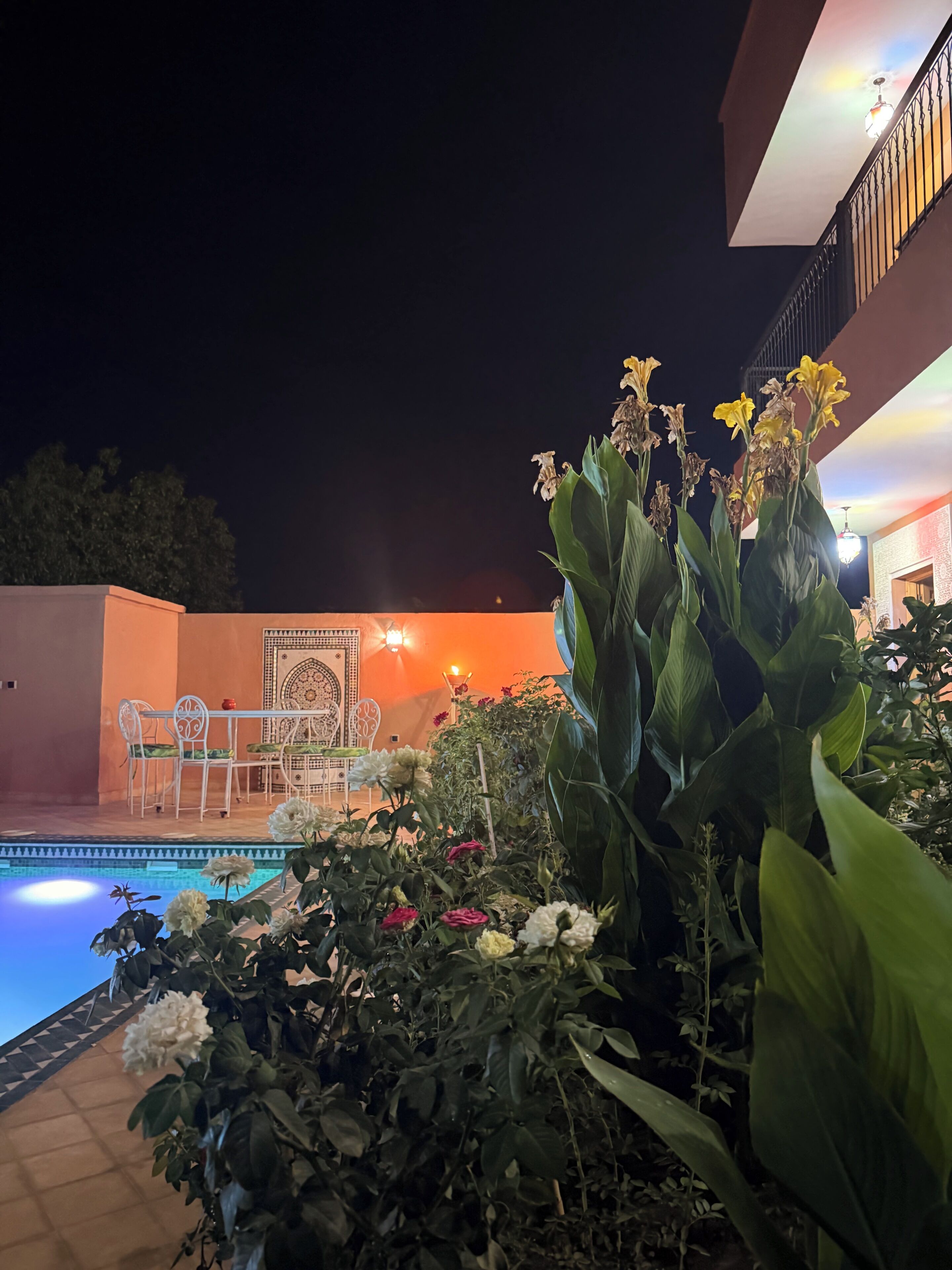 An outdoor pool area with a dining set and a decorative wall.
