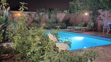 Un área de piscina con sillones reclinables y cielo nocturno.