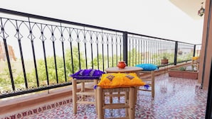Un balcón con suelo estampado, una mesa de madera y dos sillas con cojines de colores.