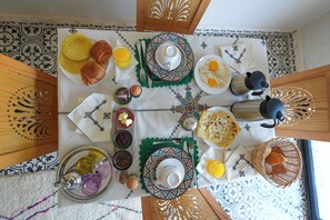 Una mesa de desayuno dispuesta con diversos platos, entre ellos huevos, tostadas y una bebida.