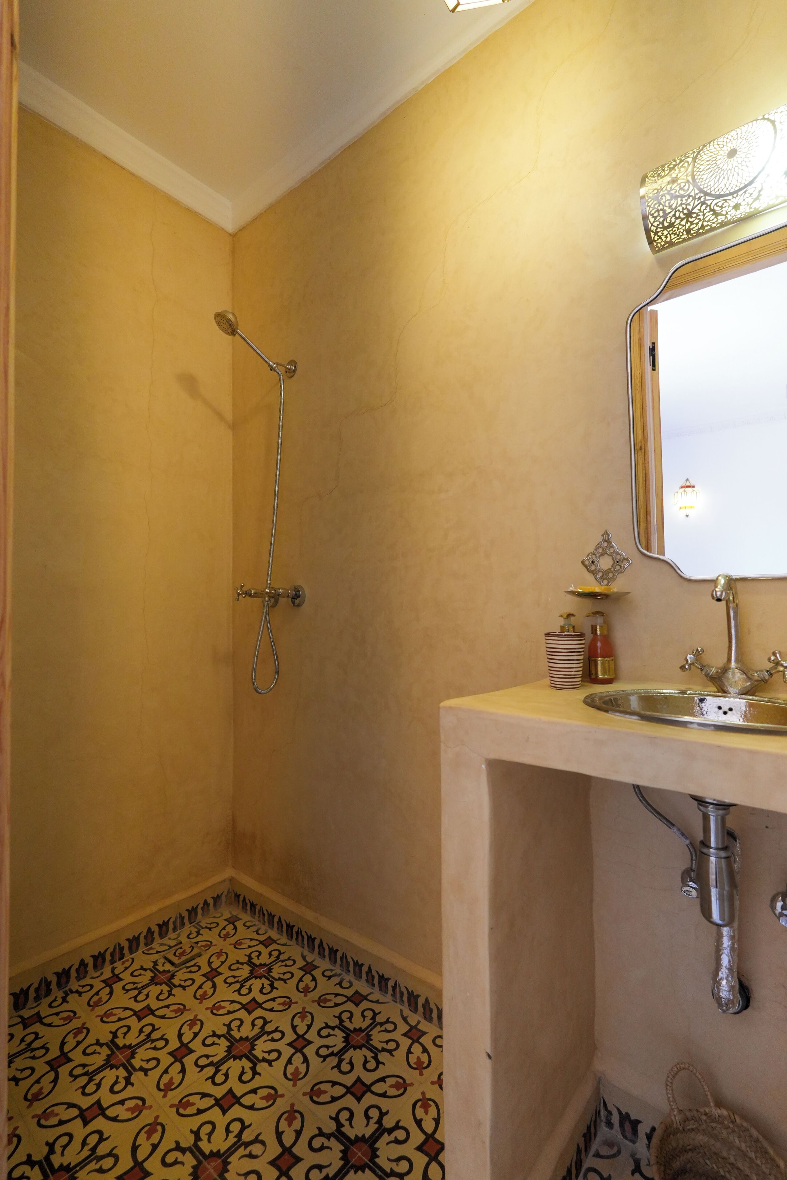 A bathroom with a shower, sink, and patterned floor.
