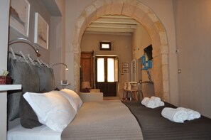 Habitación de hotel con cama, zona de estar con mesa y sillas, un espejo y un perchero.