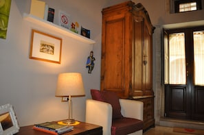 Ein Zimmer mit einem Holzschrank, einem gerahmten Bild, einer Lampe und einem Stuhl.