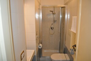 Un baño pequeño y moderno con ducha, inodoro y toallero.