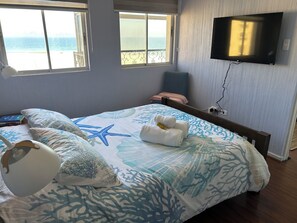 A bedroom with a bed, a TV, and a view of the sea. - Breathtaking Views on Avenida del Mar (La Serena)