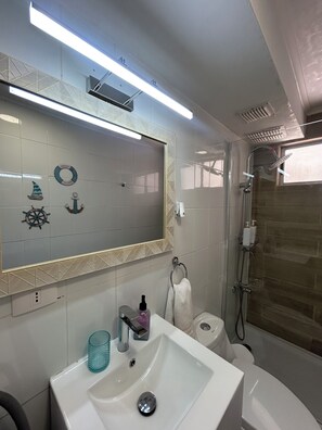 Een badkamer met een grote spiegel, een wastafel, toilet en een douchehoek.