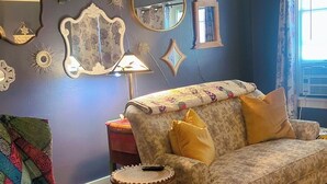 Una sala de estar con un sofá estampado, un sillón colorido y una mesita auxiliar.