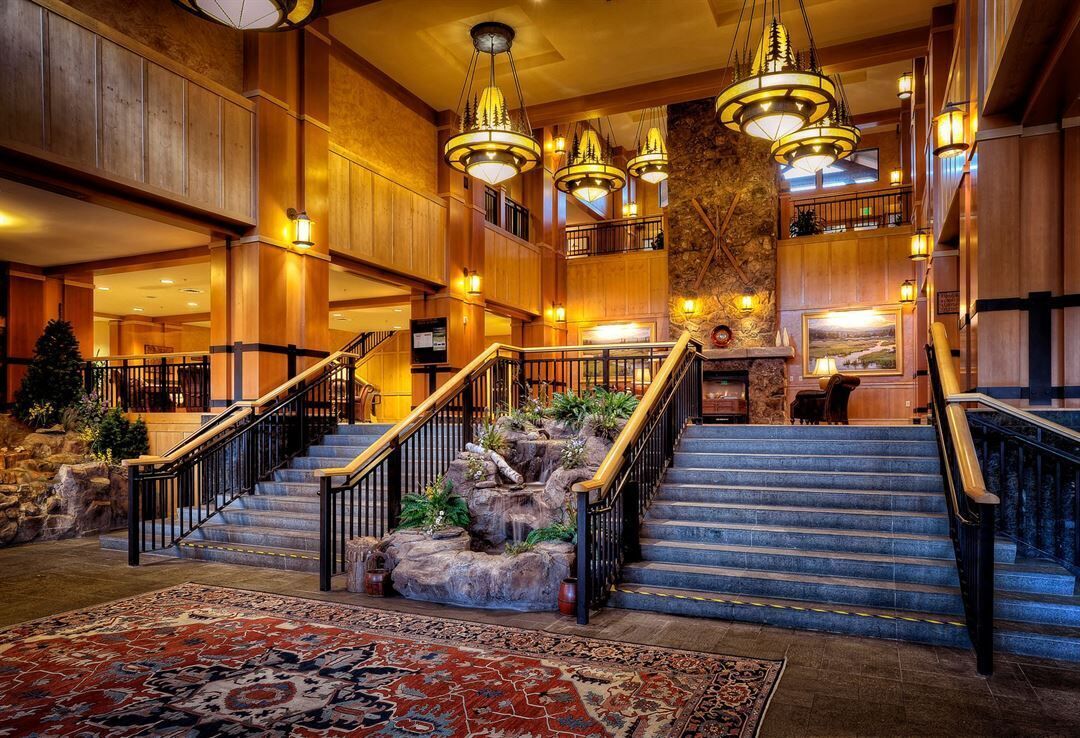 A grand lobby with a central staircase, multiple levels, and a large chandelier.