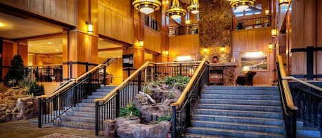 A grand lobby with a central staircase, multiple levels, and a large chandelier.