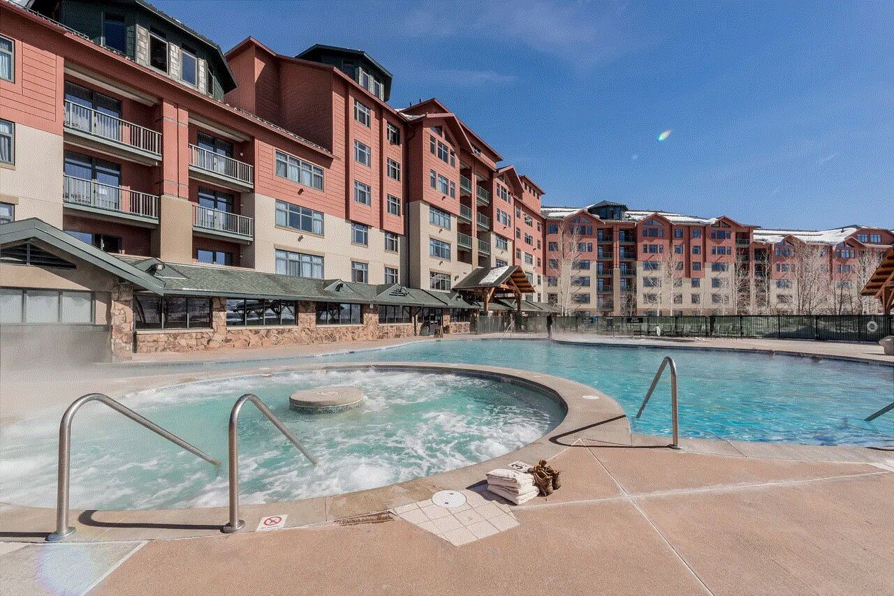 A hotel with a swimming pool, outdoor seating, and multiple balconies.