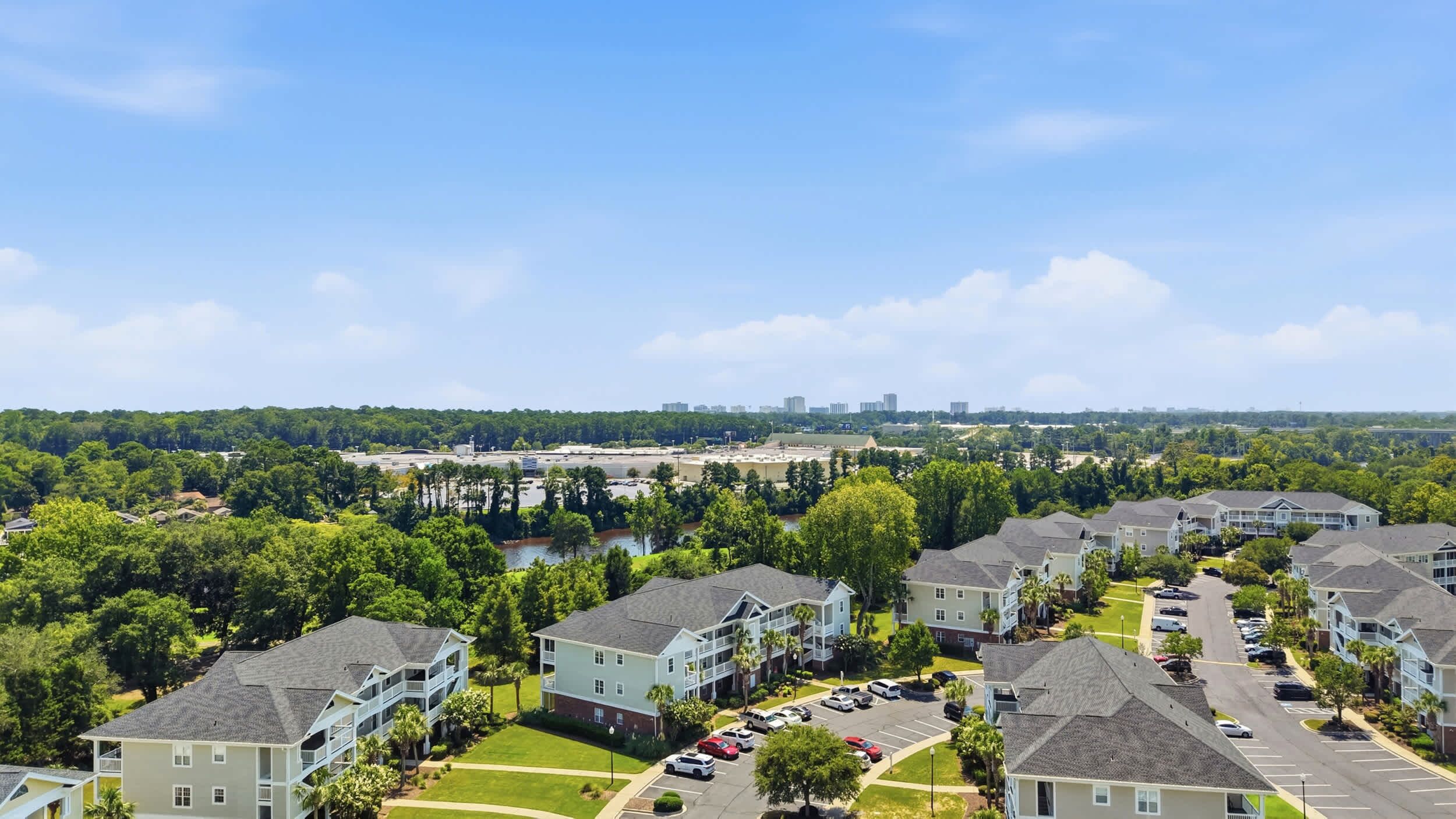 Een woonwijk met meerverdiepingen tellende huizen, een parkeerplaats en een verre skyline.