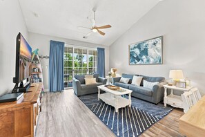 A modern living room with a sofa, coffee table, and a television. - Salt and Sand Villa at Barefoot Resort (North Myrtle Beach)
