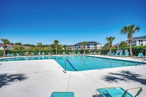 Ein Pool mit Liegestühlen und Palmen.