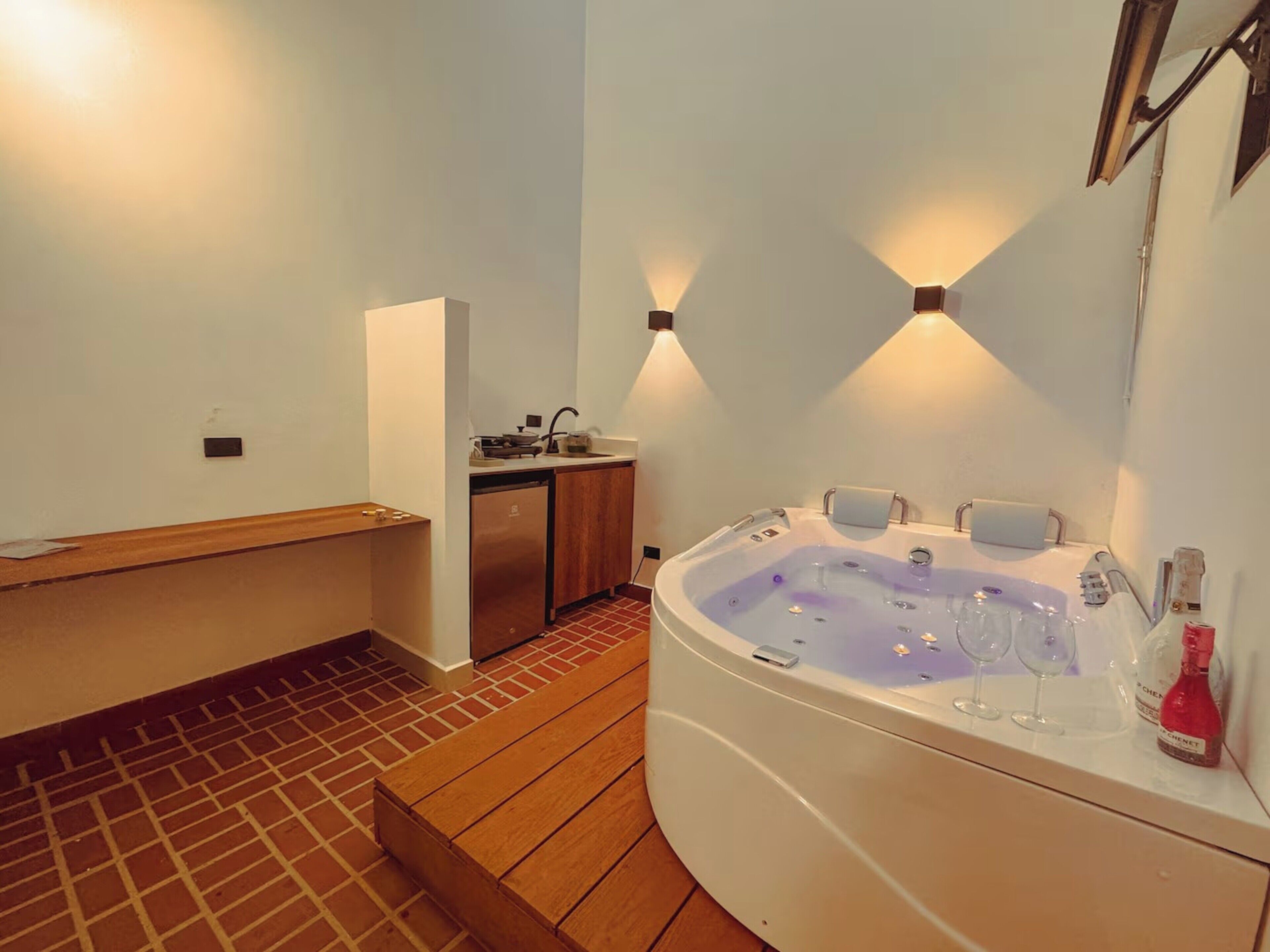 Un baño con un banco de madera, una bañera y un lavamanos.