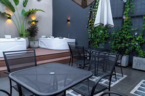 Un'area patio con posti a sedere esterni, inclusi tavolino e sedie in metallo, e una vasca idromassaggio.