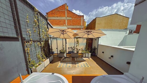 Un patio en la azotea con dos jacuzzis, mobiliario exterior y vistas de la ciudad.