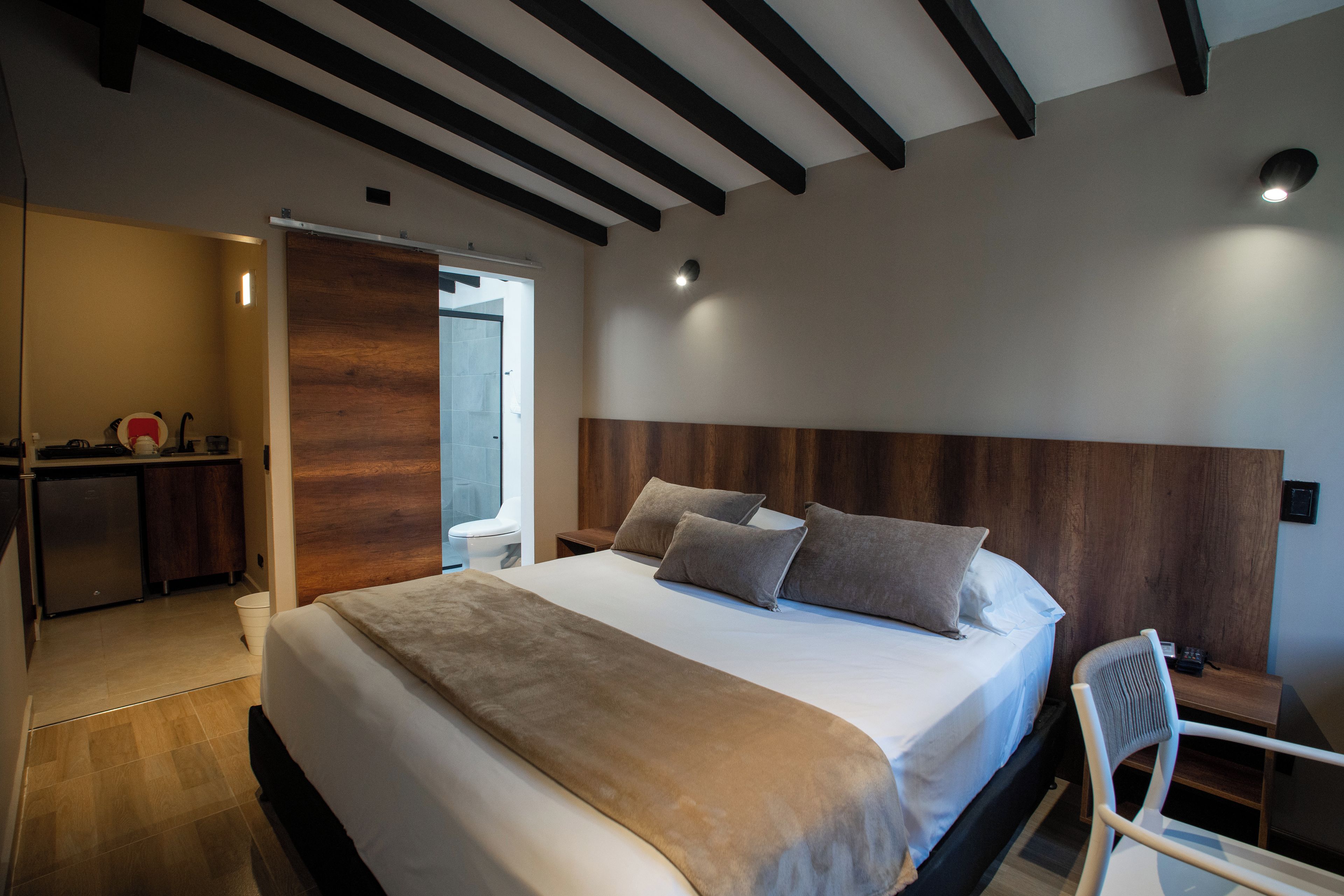 Une chambre à coucher avec un grand lit, une tête de lit en bois, une table de chevet et une chaise.