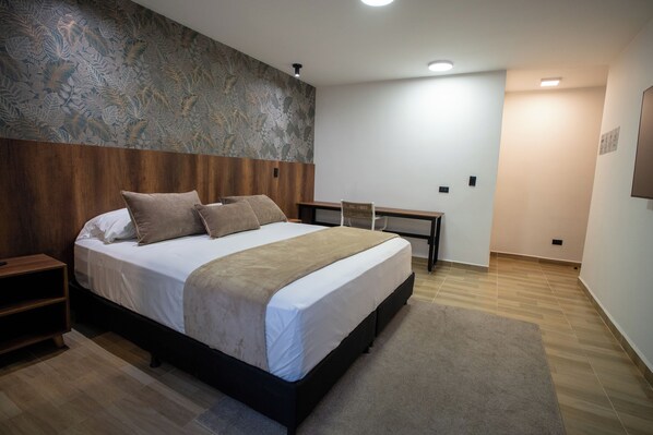 A modern bedroom with a large bed, wooden headboard, and a patterned wall.