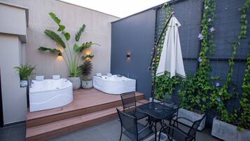En terrasse med jacuzzi, siddepladser og krukker med planter.