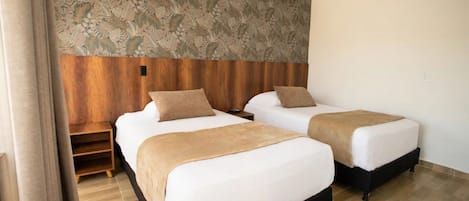 A hotel room with two beds, a wooden headboard, a patterned wall, and a wooden floor.