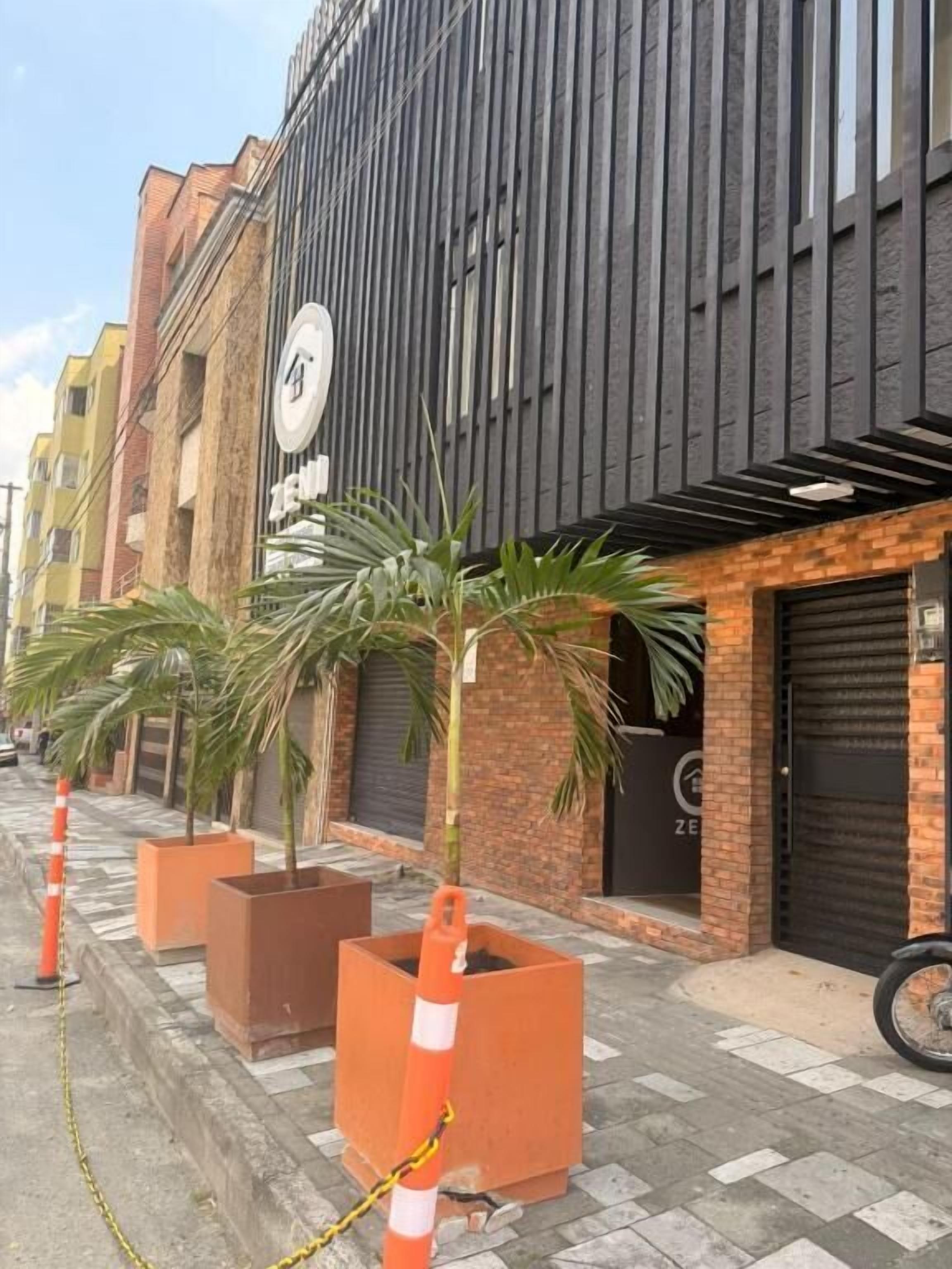 Un edificio con fachada moderna, entrada visible y macetas con plantas al frente.