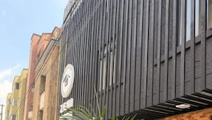 Un edificio con fachada moderna, entrada visible y macetas con plantas al frente.