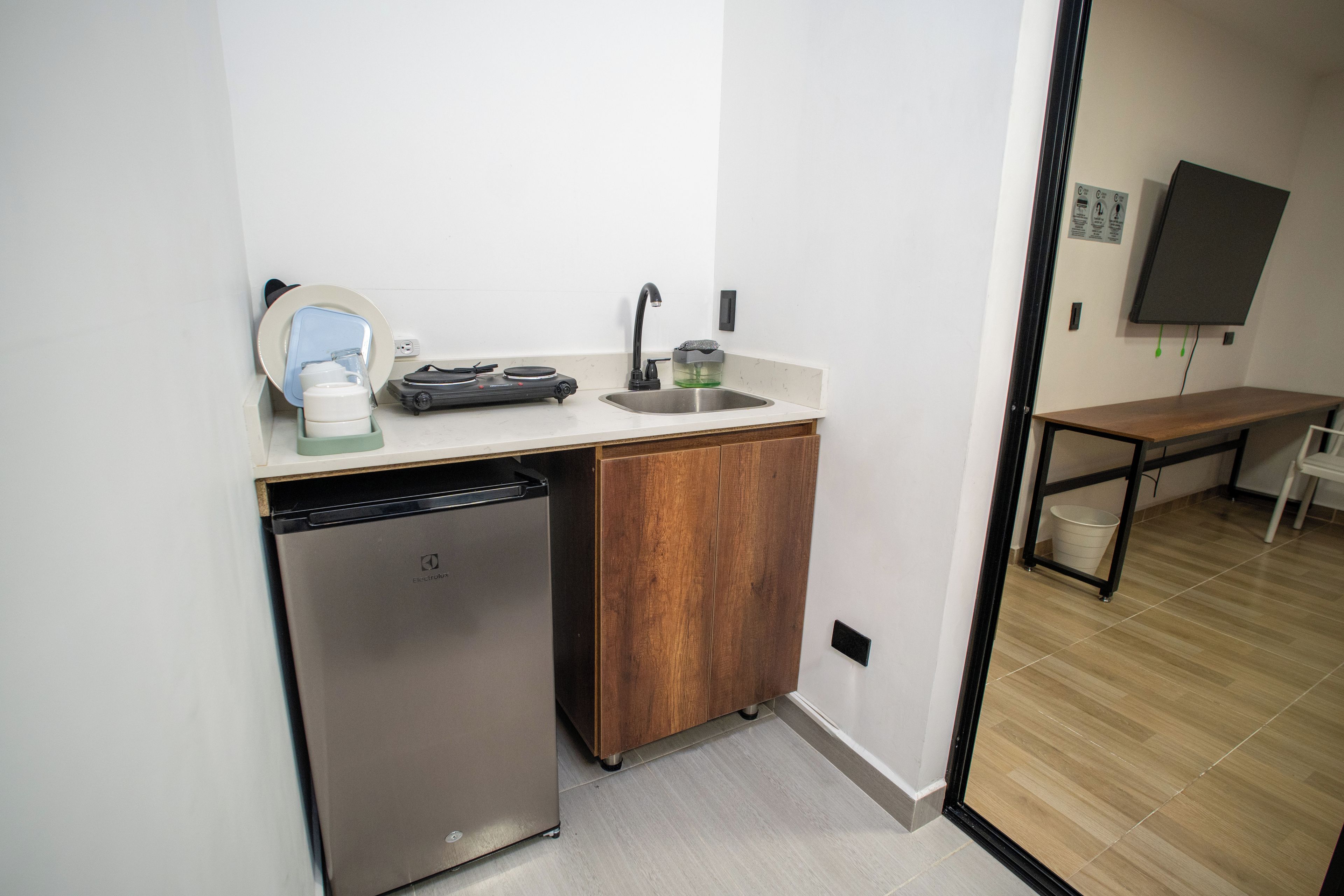 Una kitchenette compacta con lavavajillas integrado, un lavamanos pequeño y una estufa compacta.