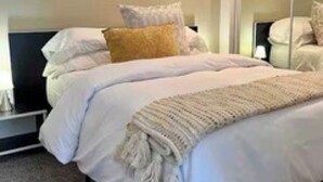 A bedroom with a bed, pillows, a bedside table, and a mirror. - Location, location location! (Seattle)