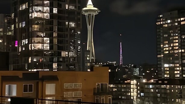 A nighttime cityscape with the Space Needle illuminated, surrounded by high-rise buildings. - Location, location location! (Seattle)
