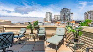A rooftop terrace with lounge chairs, potted plants, and a view of high-rise buildings. - Location, location location! (Seattle)