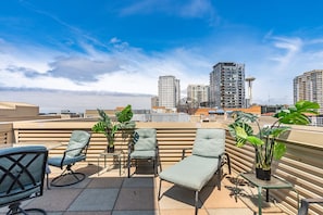 A rooftop terrace with lounge chairs, potted plants, and a view of high-rise buildings. - Location, location location! (Seattle)