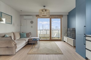 A modern living room with a sofa, a coffee table, and a TV. - PORTO 46 - Letnica Sea&City Gdańsk (Gdańsk)